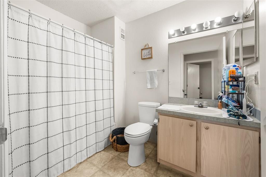 3705 Southwest 27th Street, Unit 615 Gainesville, FL 32608 - Photo 16 of 27 a bathroom with a sink a toilet and shower curtain