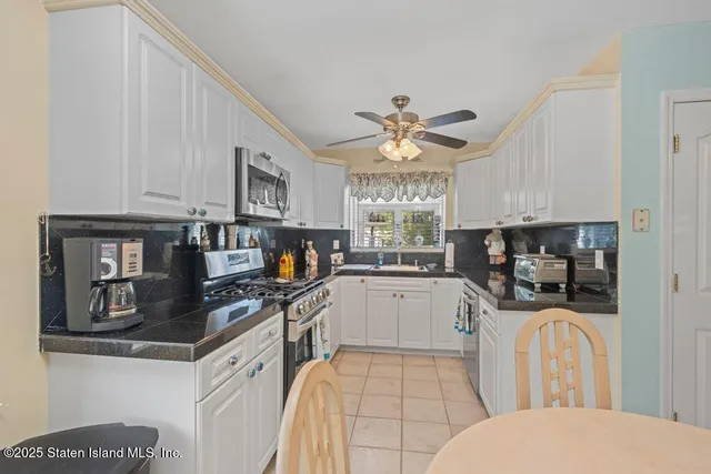 a kitchen with stainless steel appliances a sink a stove cabinets dining table and chairs
