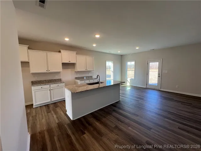 a large kitchen with stainless steel appliances granite countertop a large counter top a stove and a wooden floors