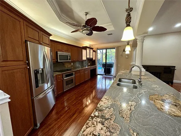 a kitchen with stainless steel appliances granite countertop a refrigerator a stove and a sink with wooden floor