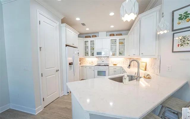 a large white kitchen with sink and a refrigerator