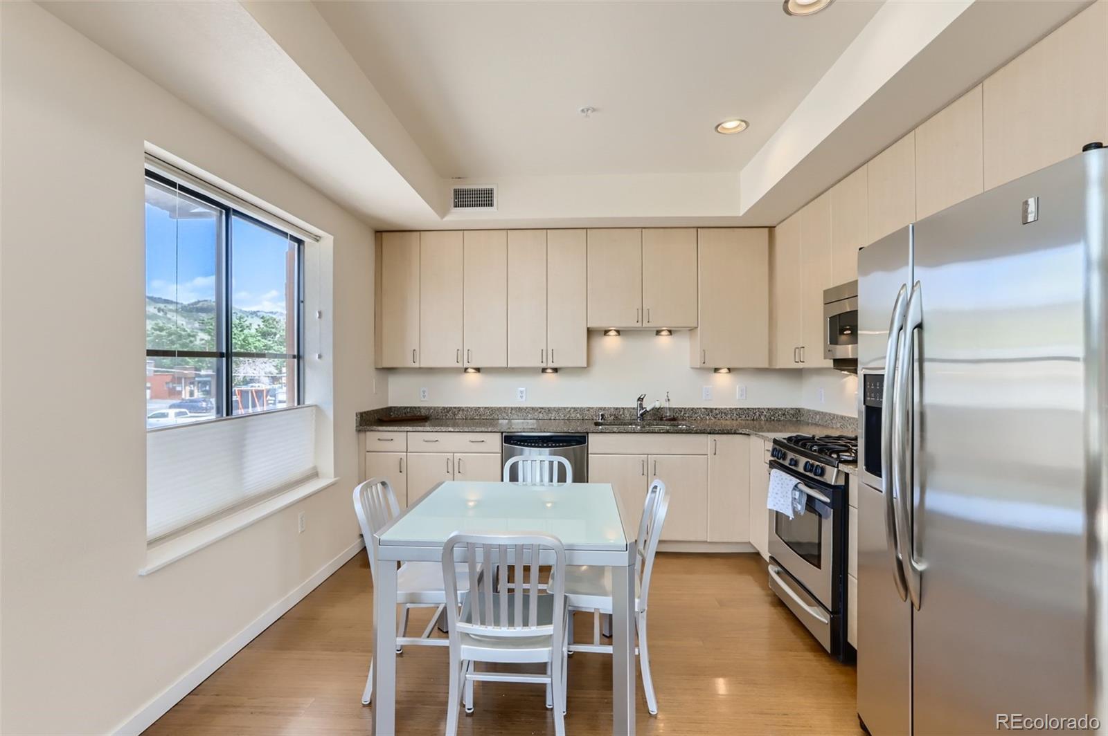 4580 Broadway, Unit 223 Boulder, CO 80304 - Photo 8 of 28 a kitchen with a refrigerator a stove a sink and white cabinets with wooden floor