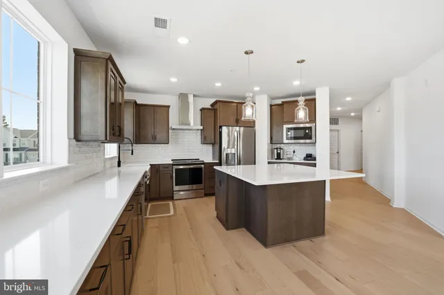 a large kitchen with stainless steel appliances a large counter top a stove and a sink