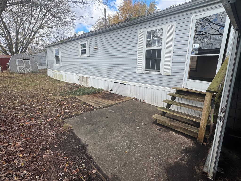 View of property exterior featuring a patio area, entry steps, and a storage unit