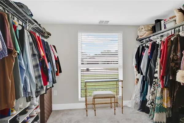a view of walk in closet with clothes and shoes