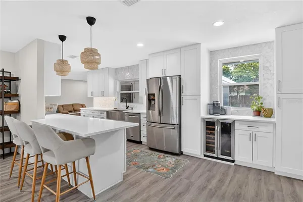 a kitchen with stainless steel appliances a stove a refrigerator a sink dishwasher a oven with white cabinets and wooden floor