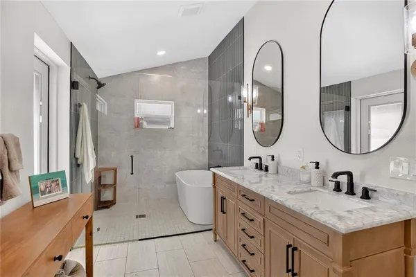 a bathroom with a double vanity sink mirror and bathtub