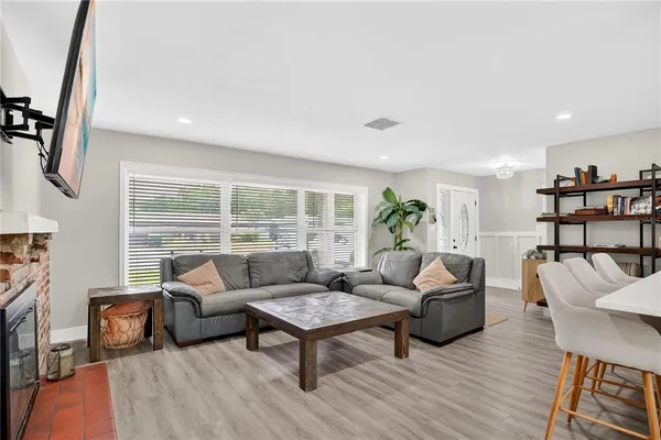 a living room with furniture a large window and wooden floor