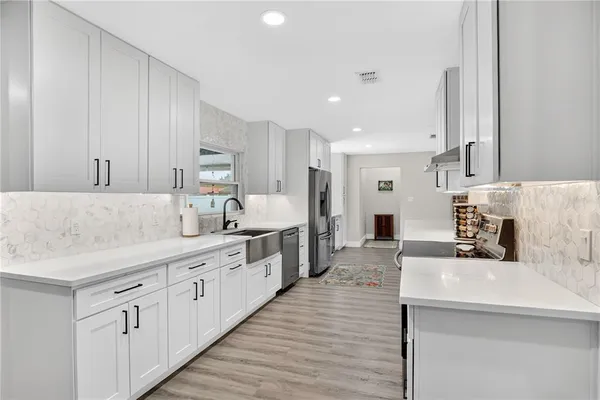 a large kitchen with stainless steel appliances kitchen island granite countertop a sink and dishwasher a stove with wooden floors