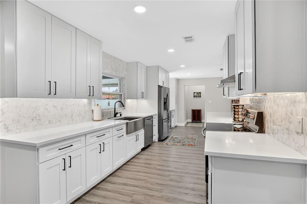 4222 Old Dominion Road Orlando, FL 32812 - Photo 10 of 49 a large kitchen with stainless steel appliances kitchen island granite countertop a sink and dishwasher a stove with wooden floors