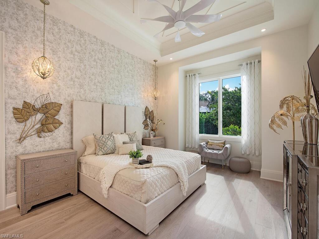 714 Killdeer Place Naples, FL 34108 - Photo 17 of 34 a bedroom with a large bed and a chandelier