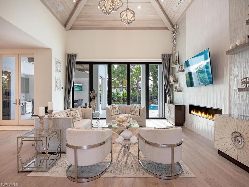 714 Killdeer Place Naples, FL 34108 - Photo 9 of 34 a living room with fireplace furniture and a floor to ceiling window