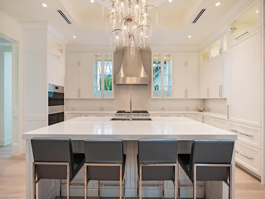 714 Killdeer Place Naples, FL 34108 - Photo 10 of 34 a kitchen with a dining table chairs cabinets and stainless steel appliances
