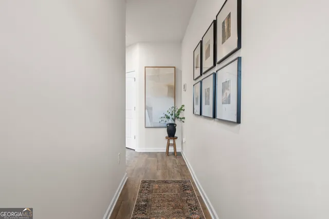 a view of a hallway with wooden floor and a bathroom