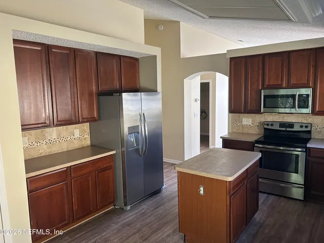 a kitchen with stainless steel appliances granite countertop a refrigerator a stove and wooden cabinets