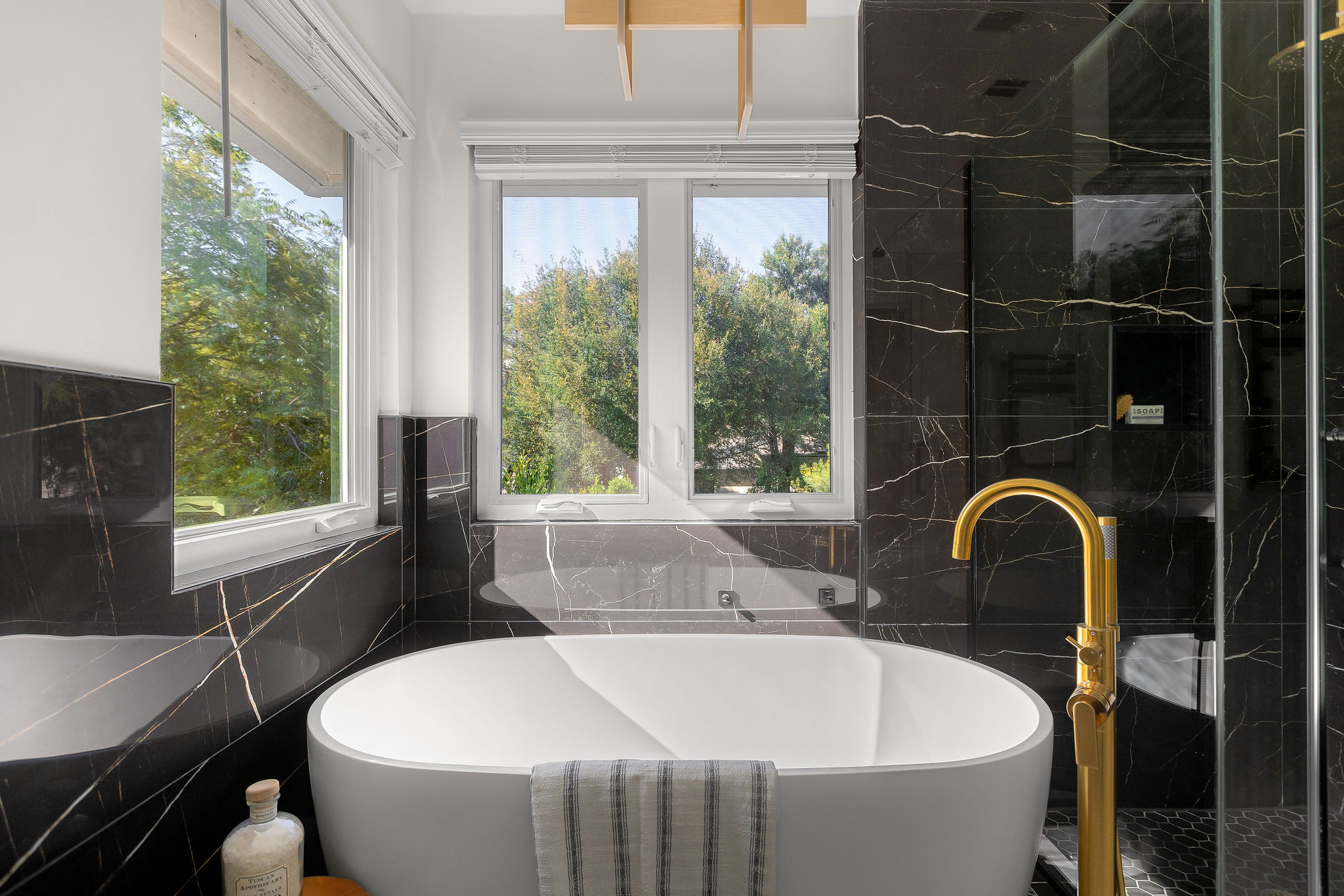 6500 Clay Allison Pass Austin, TX 78749 - Photo 26 of 39 Freestanding soaking tub with a floor-mounted brass faucet, surrounded by black tiled walls with white veining