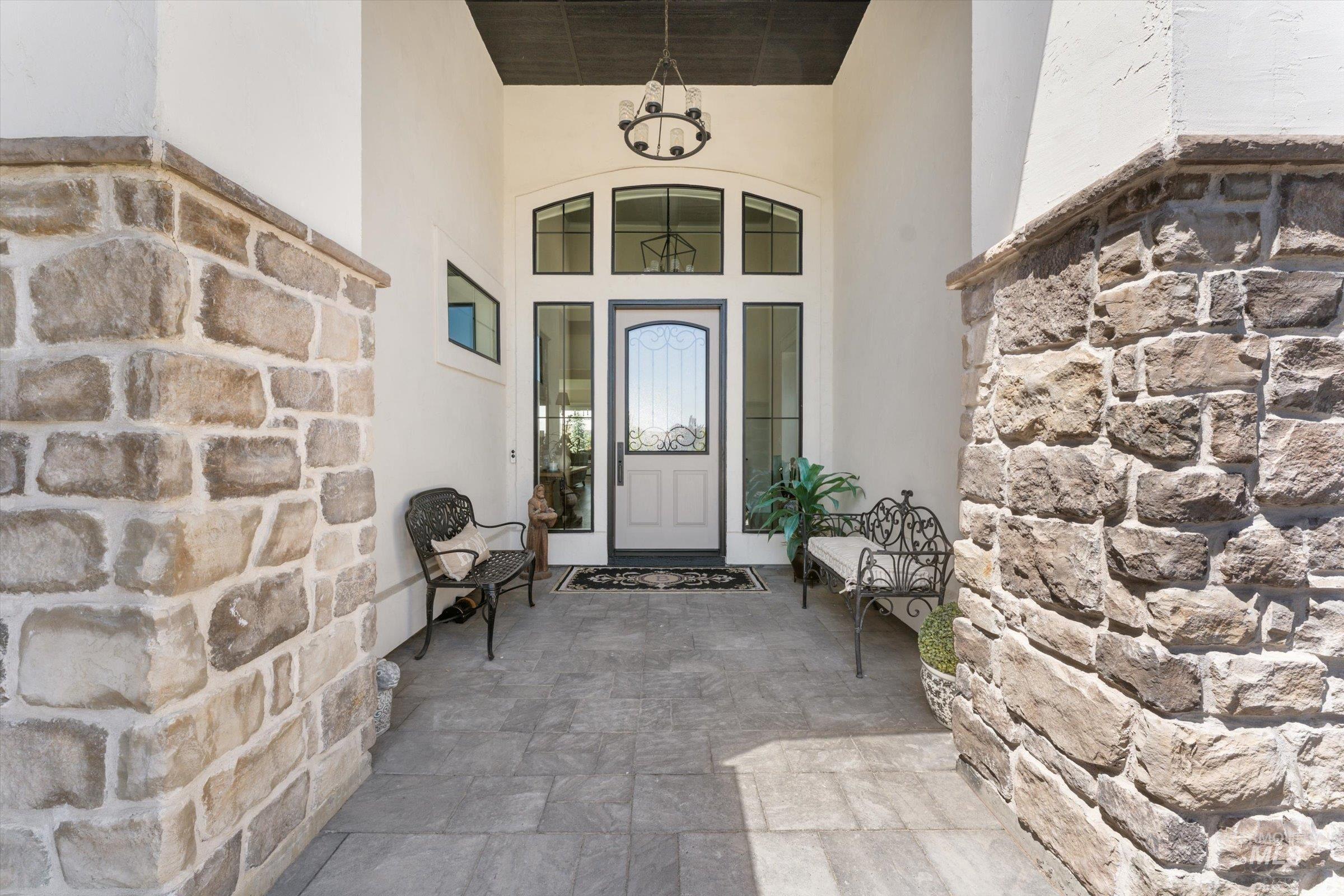 6585 South Pemberley Way Meridian, ID 83642 - Photo 5 of 43 Entryway featuring stone columns, a high ceiling with a chandelier, and a transom window above the main door