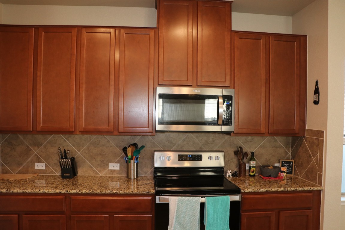 321 Parrot Tulip View Pflugerville, TX 78660 - Photo 14 of 33 a kitchen with granite countertop wooden cabinets and a stove top oven
