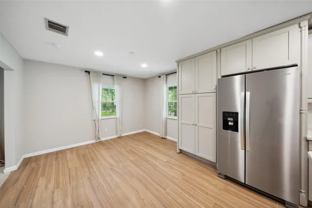 a view of a kitchen with a refrigerator and wooden floor