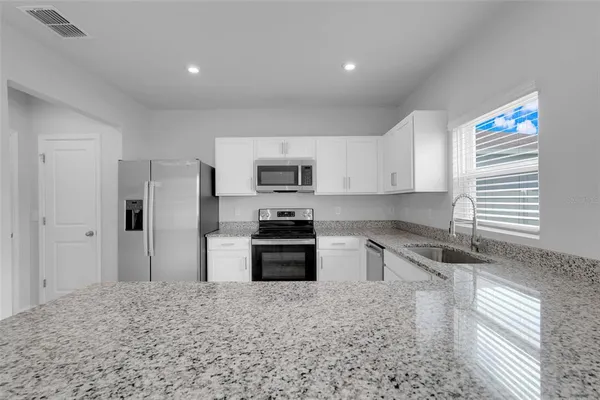 a kitchen with granite countertop a refrigerator and a sink