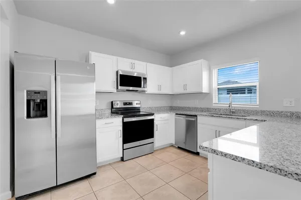 a kitchen with granite countertop a refrigerator stove and sink