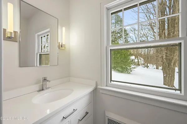 a bathroom with a granite countertop sink and a window