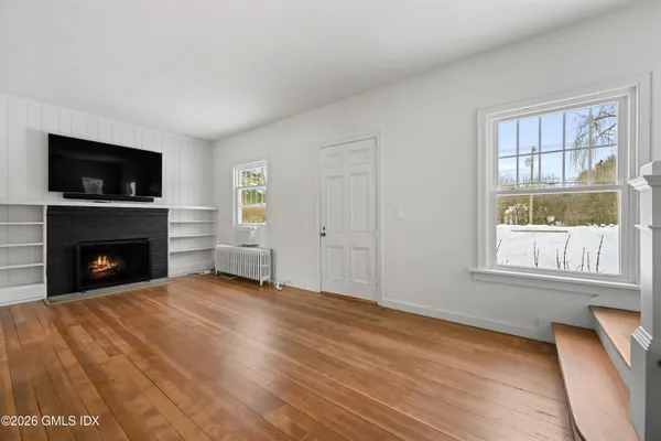 a view of an empty room with a window and fireplace