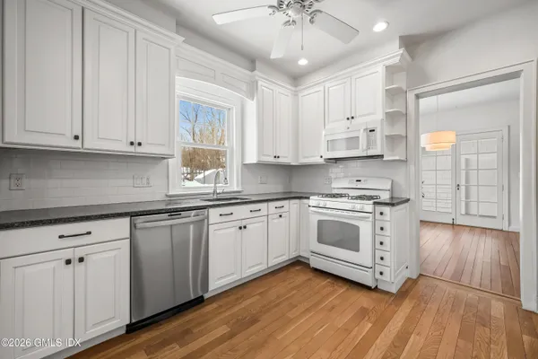 a kitchen with granite countertop white cabinets and white appliances