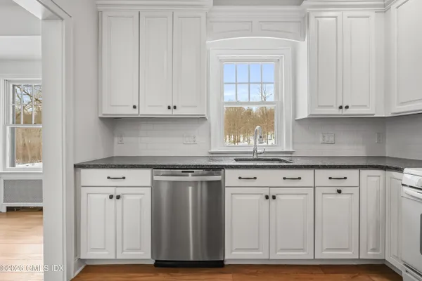 a kitchen with granite countertop white cabinets and sink