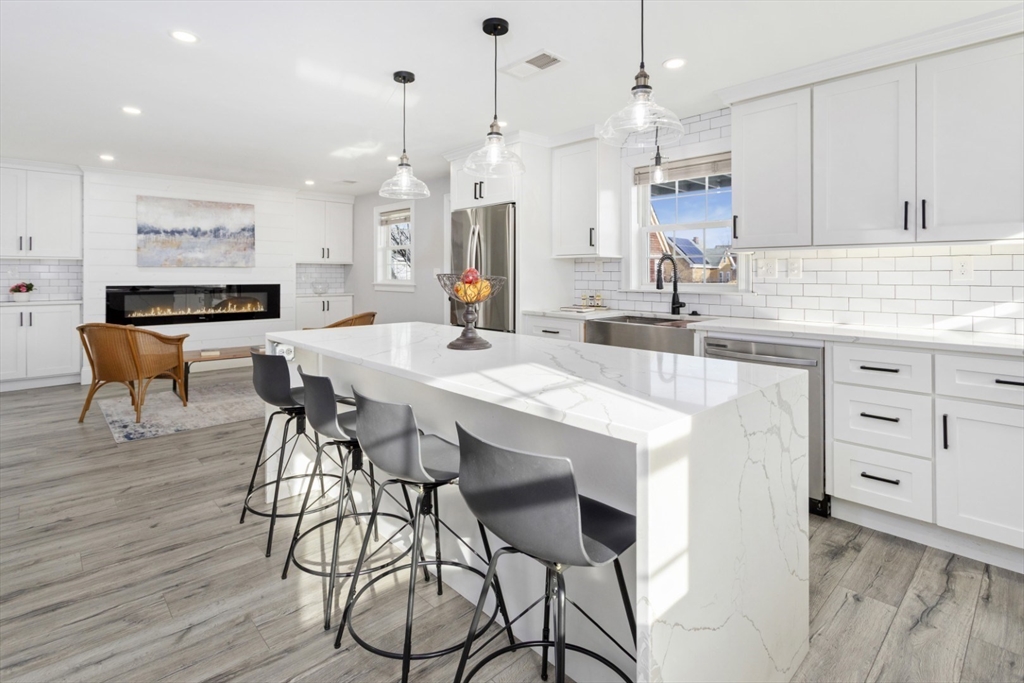 87 Otis Street, Unit 2 Medford, MA 02155 - Photo 6 of 42 a kitchen with stainless steel appliances kitchen island wooden floors and white cabinets