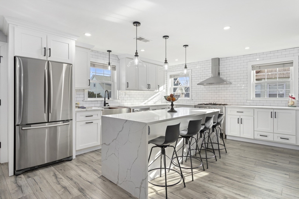 87 Otis Street, Unit 2 Medford, MA 02155 - Photo 7 of 42 a kitchen with stainless steel appliances kitchen island granite countertop a refrigerator a stove a sink and white cabinets with wooden floor