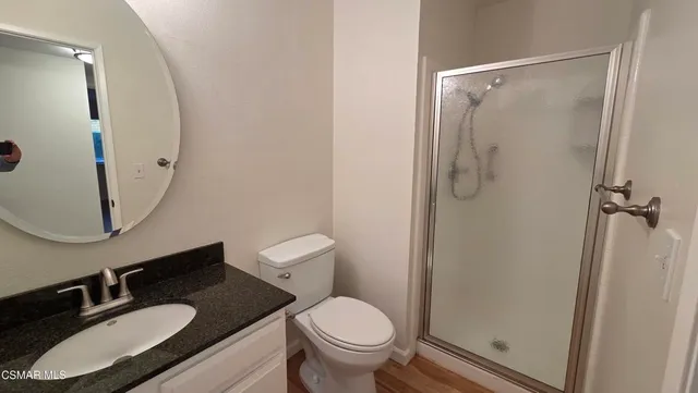 a bathroom with a granite countertop sink toilet a mirror a vanity and shower