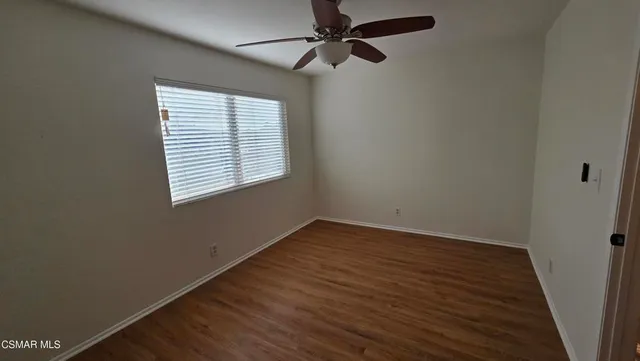 an empty room with wooden floor fan and windows