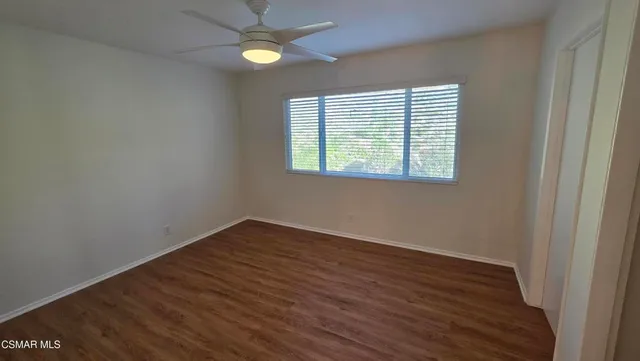 an empty room with wooden floor closet and windows