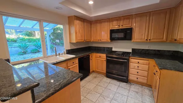 a kitchen with stainless steel appliances granite countertop a stove a sink and a microwave