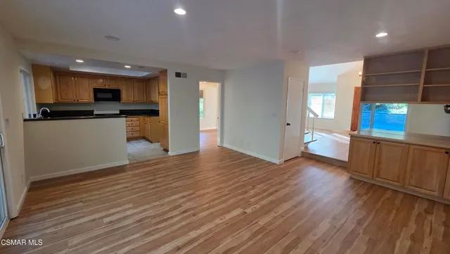 a view of a kitchen with kitchen island a sink wooden floor and stainless steel appliances
