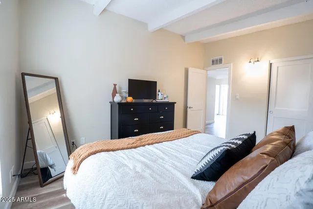 a bedroom with a bed and a flat tv screen on a dresser