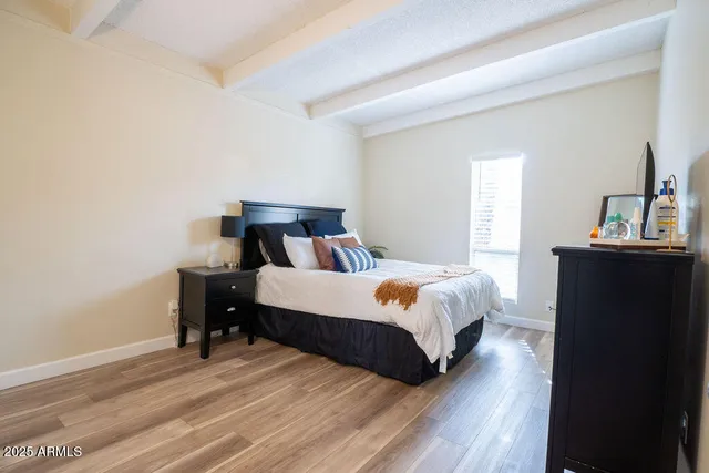 a bed sitting in a bedroom next to a window with pc on table and a window
