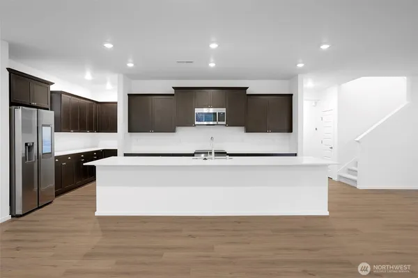 a view of kitchen with stainless steel appliances kitchen island a refrigerator sink and white cabinets