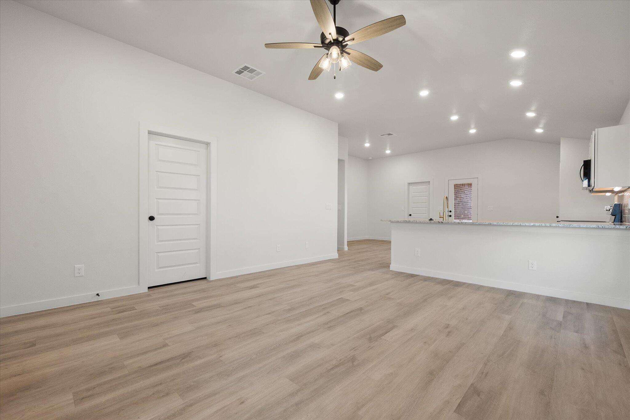 3022 138th Place Lubbock, TX 79423 - Photo 4 of 20 a view of an empty room with kitchen appliances and a ceiling fan