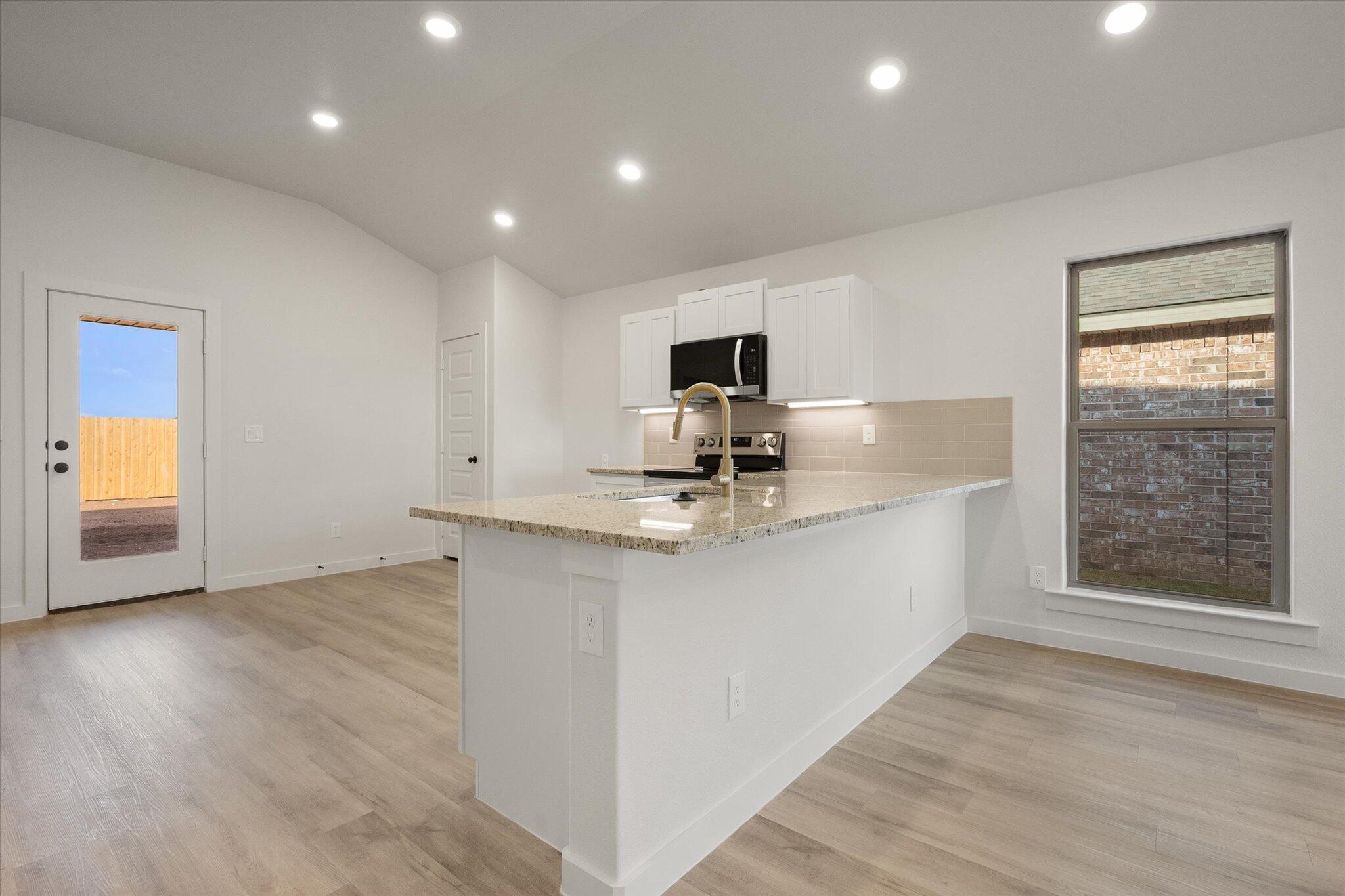 3022 138th Place Lubbock, TX 79423 - Photo 8 of 20 a kitchen with granite countertop a stove a sink and a refrigerator