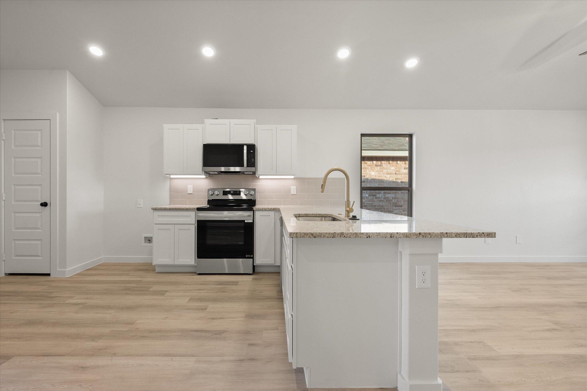 3022 138th Place Lubbock, TX 79423 - Photo 9 of 20 a kitchen with a sink and a stove top oven with wooden floor
