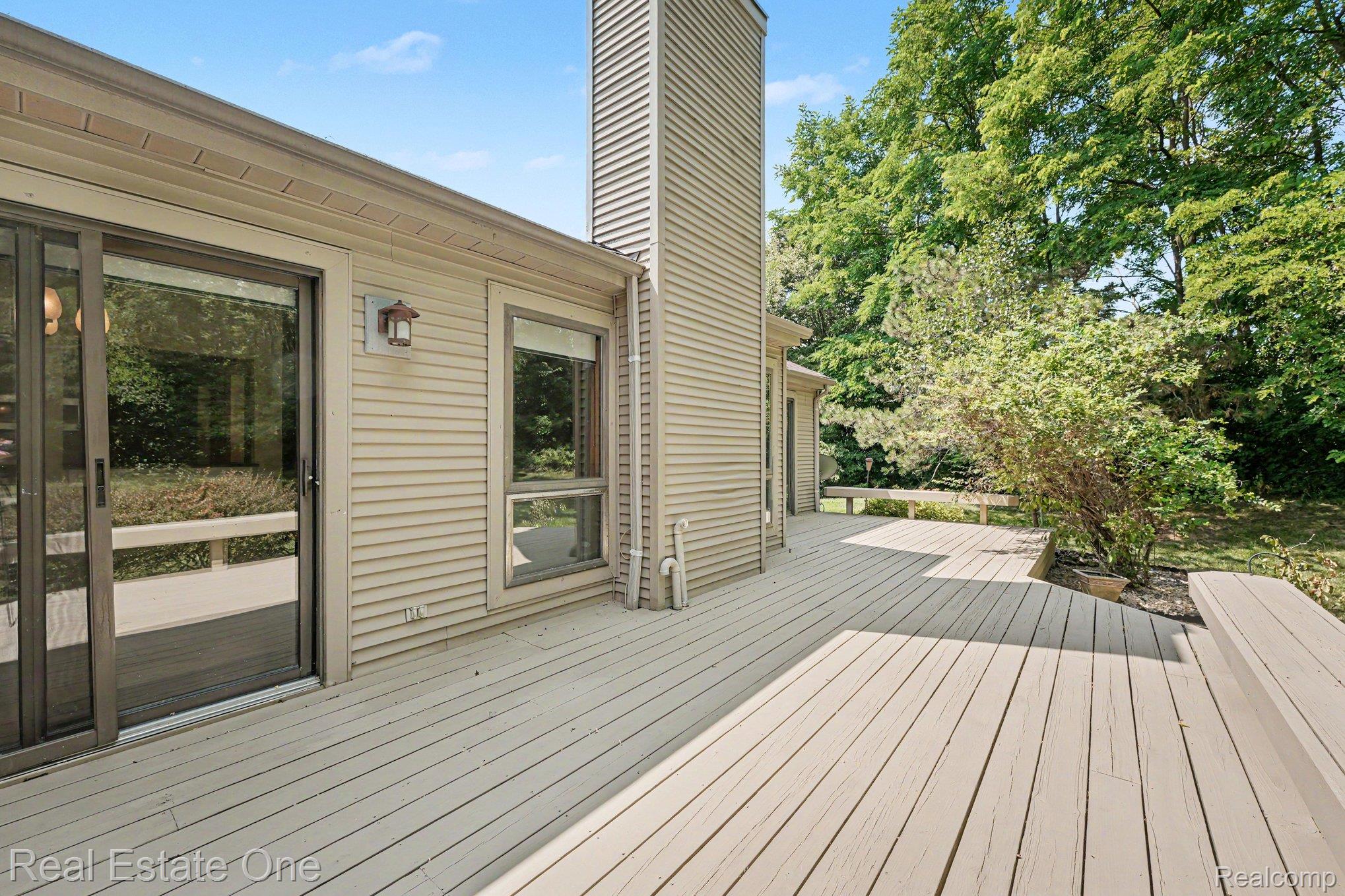 701 Charing Court Rochester, MI 48307 - Photo 25 of 29 Expansive outdoor deck featuring wood-finish flooring, built-in benches, and mature landscaping