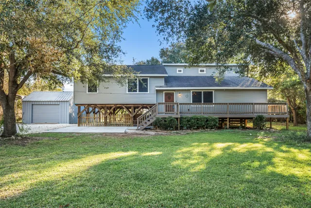 a view of a house with a yard and a large tree