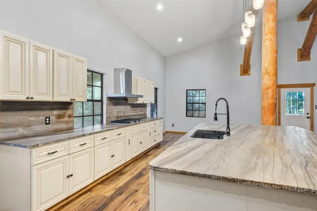 a large kitchen with granite countertop white cabinets and stainless steel appliances