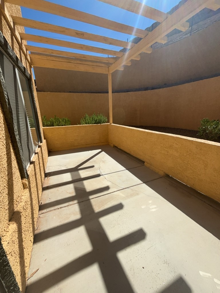 4915 East Russell Road, Unit 154 Las Vegas, NV 89120 - Photo 1 of 20 A sunny outdoor patio features a wooden pergola overhead casting architectural shadows on concrete flooring.