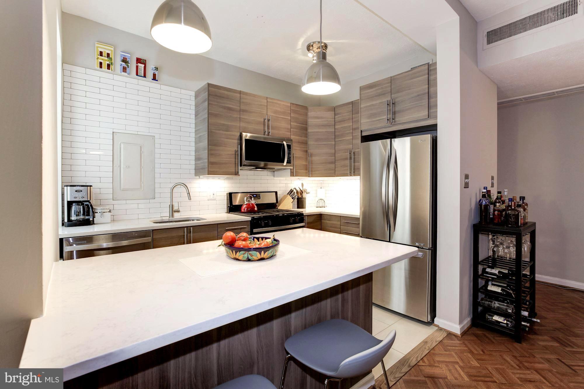 1851 Columbia Road Northwest, Unit 305 Washington, DC 20009 - Photo 3 of 28 a kitchen with a refrigerator a stove a sink and a dining table with wooden floor