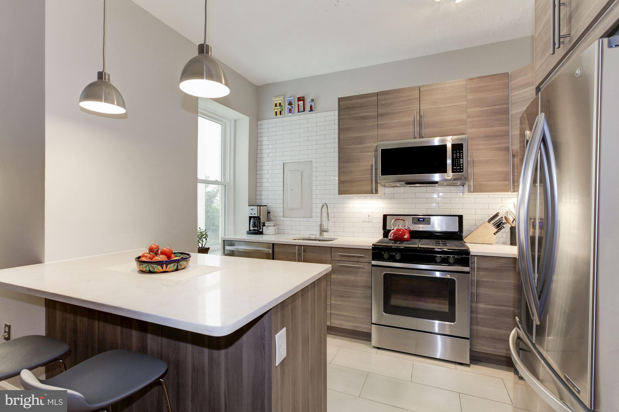 1851 Columbia Road Northwest, Unit 305 Washington, DC 20009 - Photo 4 of 28 a kitchen with stainless steel appliances a stove a sink and a refrigerator