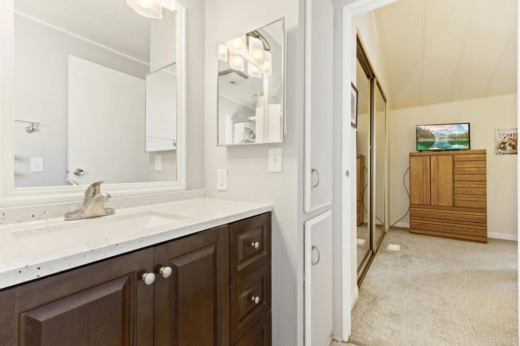 1476 Dover Street Oceanside, CA 92057 - Photo 26 of 45 a bathroom with a granite countertop sink a mirror a vanity and a shower