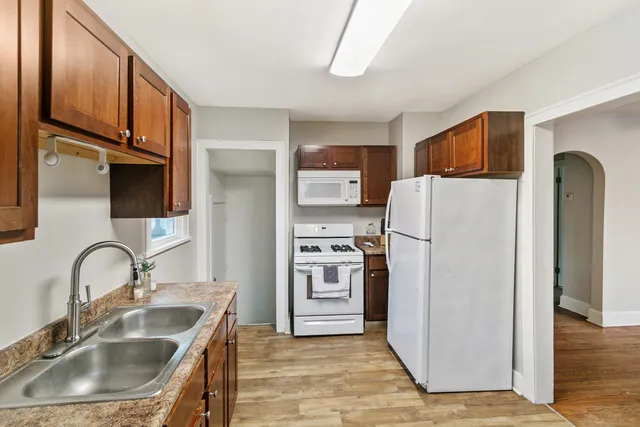 a kitchen with stainless steel appliances granite countertop a refrigerator a sink a stove and a refrigerator with wooden floor